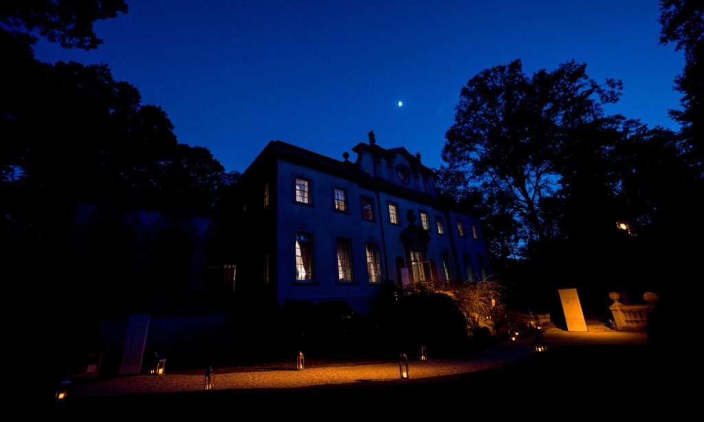 WM Events illuminated a stately building at night, with lantern-lit walkways and a crescent moon above, framed by tall trees.